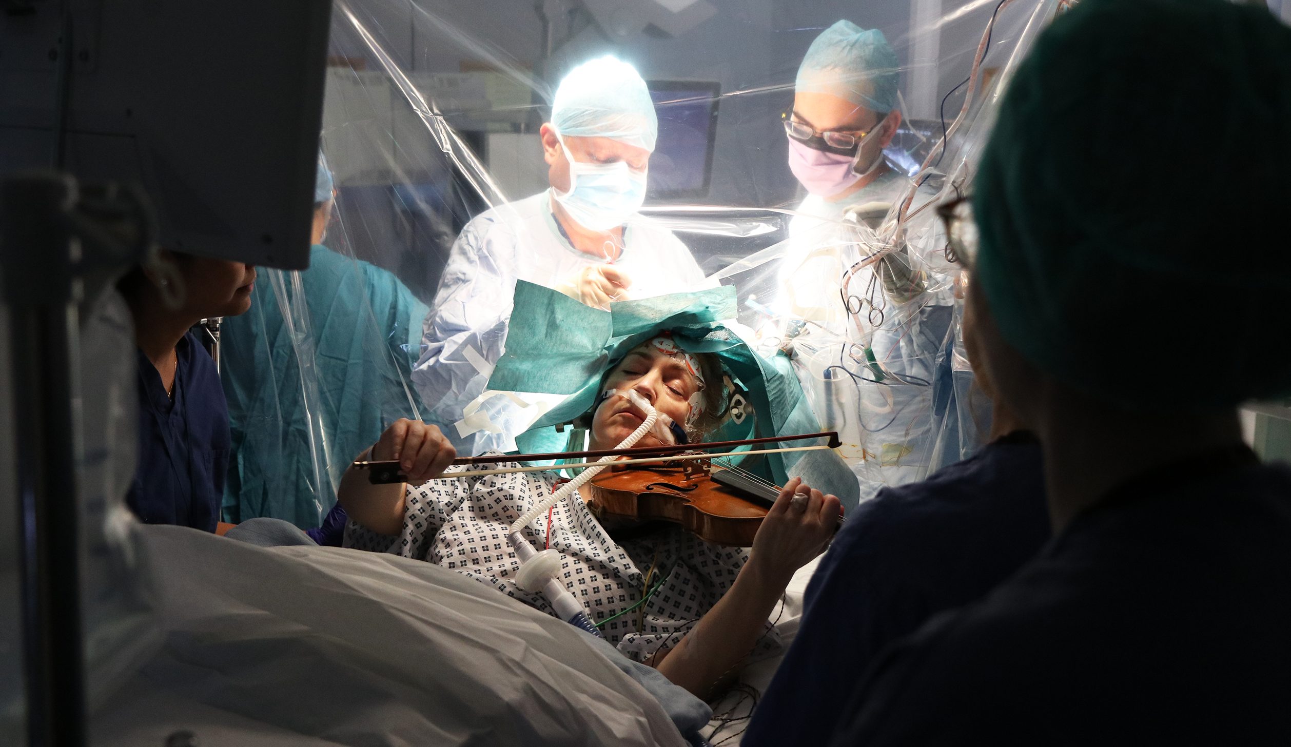 La forza di una musicista suona il violino mentre la operano per un